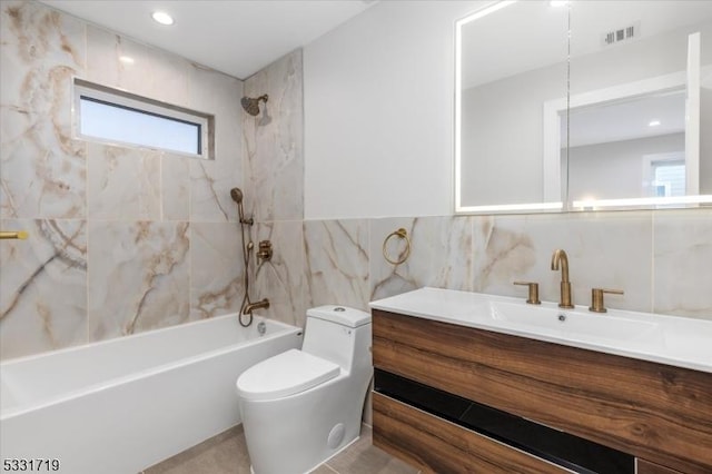 full bathroom featuring toilet, vanity, tile walls, and tiled shower / bath