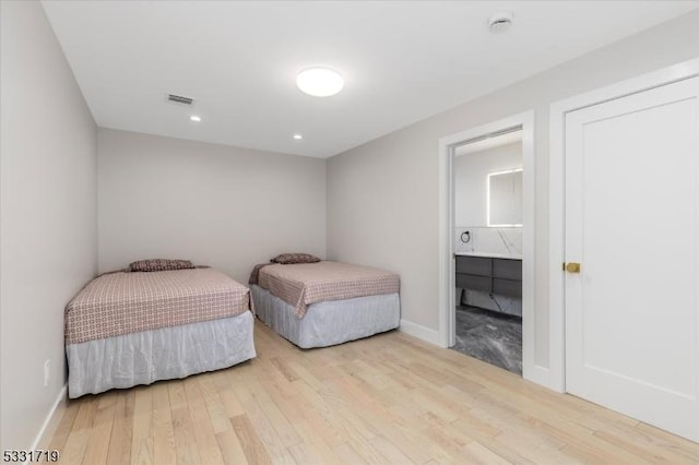 bedroom with connected bathroom and light hardwood / wood-style flooring