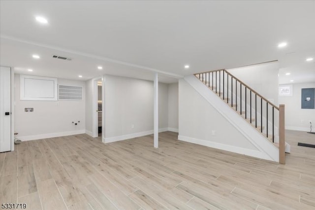 basement with light hardwood / wood-style floors and electric panel