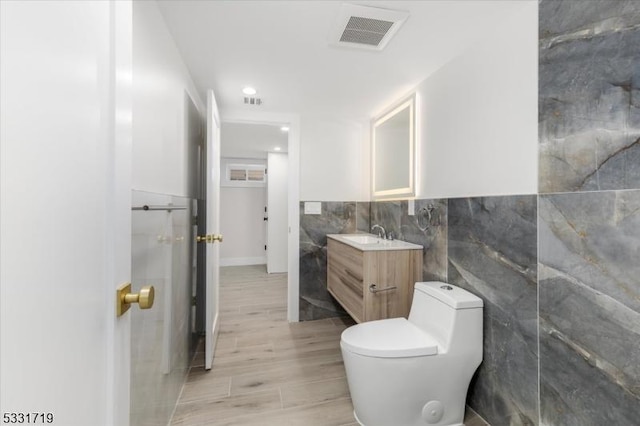 bathroom with vanity, toilet, and tile walls