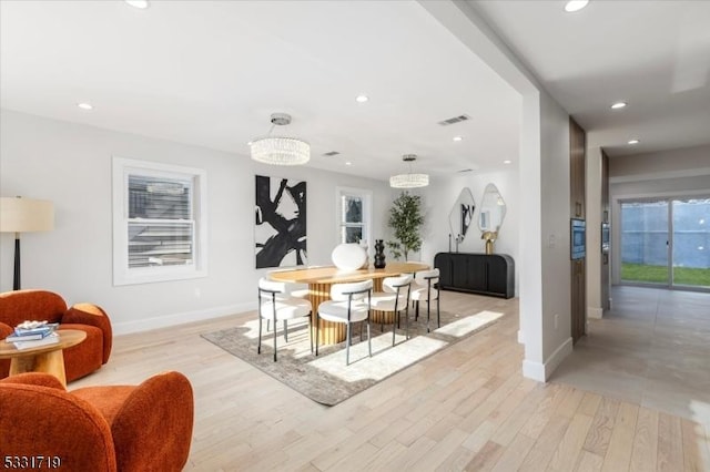 dining room with plenty of natural light, light wood-type flooring, and a notable chandelier