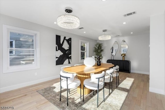 dining room featuring light wood-type flooring and an inviting chandelier