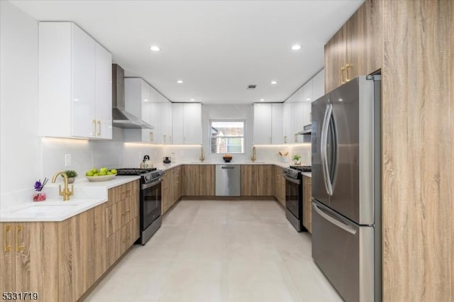 kitchen featuring backsplash, wall chimney exhaust hood, white cabinets, and appliances with stainless steel finishes