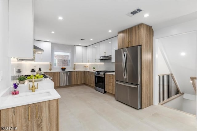 kitchen featuring decorative backsplash, sink, white cabinets, and appliances with stainless steel finishes