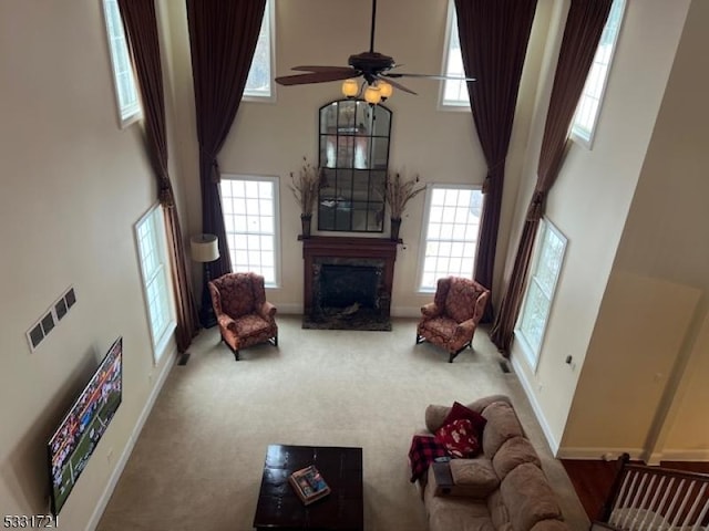 carpeted living room with a wealth of natural light, ceiling fan, and a towering ceiling