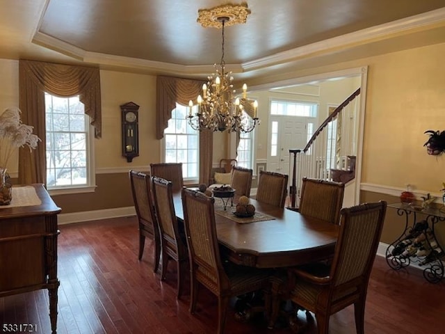 dining space featuring a raised ceiling, dark hardwood / wood-style flooring, ornamental molding, and an inviting chandelier