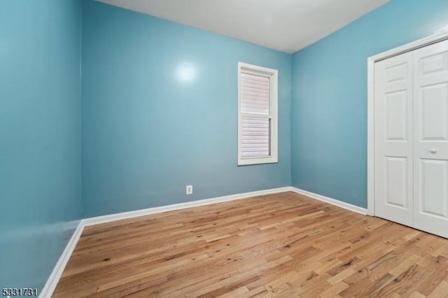 unfurnished bedroom with light hardwood / wood-style flooring and a closet