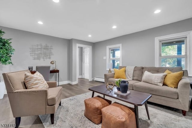 living room featuring baseboard heating, a healthy amount of sunlight, and light wood-type flooring