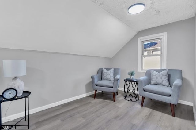 living area with a textured ceiling, lofted ceiling, and hardwood / wood-style flooring