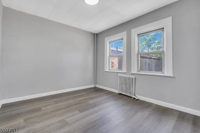 unfurnished room featuring radiator and wood-type flooring