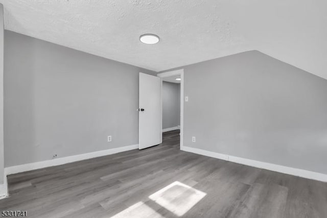 unfurnished room featuring lofted ceiling, a textured ceiling, and dark hardwood / wood-style floors