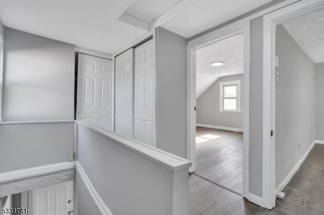 hallway featuring hardwood / wood-style flooring, a textured ceiling, and vaulted ceiling