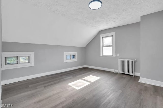 bonus room with radiator, a textured ceiling, lofted ceiling, and dark hardwood / wood-style floors