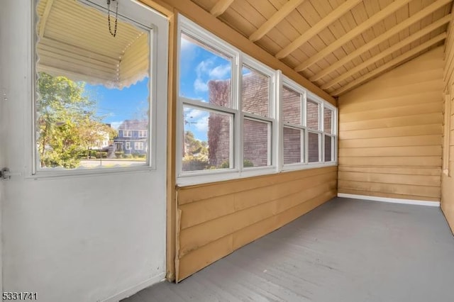 unfurnished sunroom with lofted ceiling with beams, wooden ceiling, and plenty of natural light