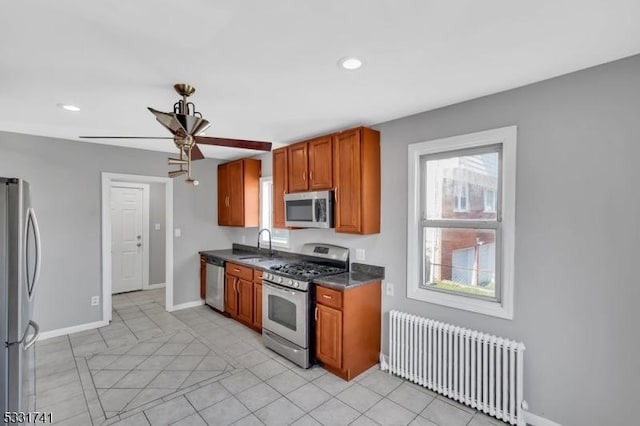 kitchen with appliances with stainless steel finishes, ceiling fan, sink, and radiator