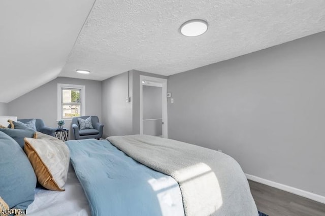 bedroom featuring a textured ceiling, vaulted ceiling, and dark wood-type flooring