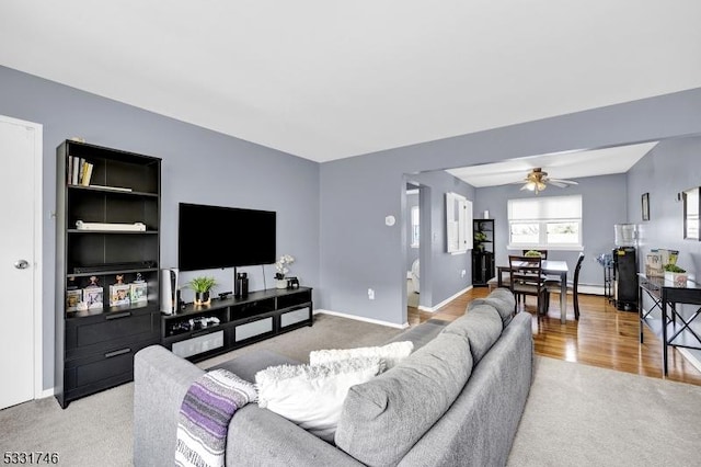 carpeted living room with ceiling fan and a baseboard heating unit