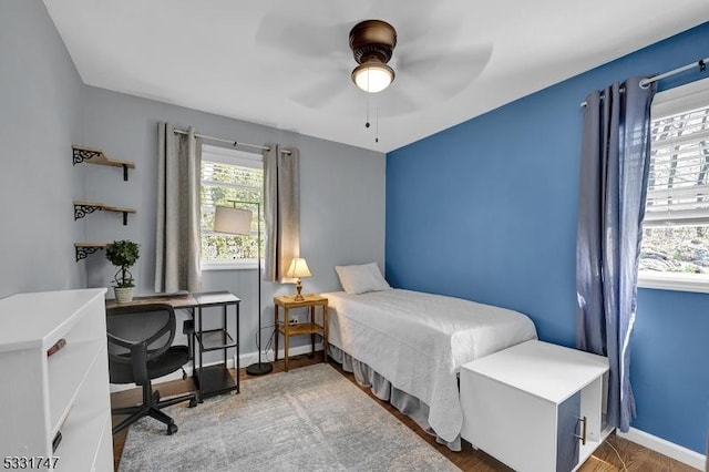 bedroom with baseboards, ceiling fan, wood finished floors, and multiple windows