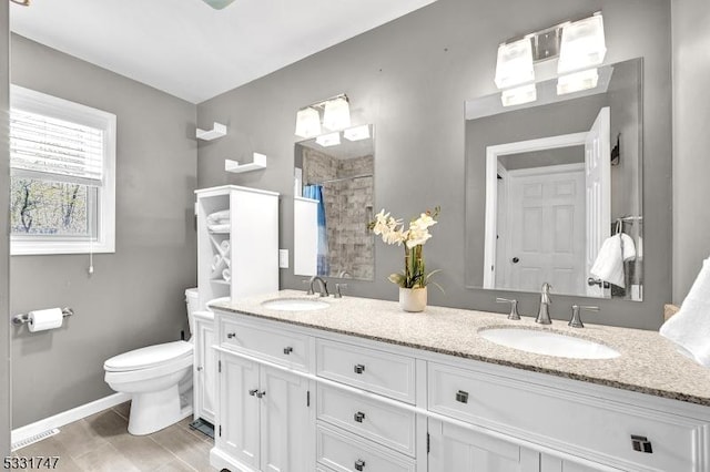 full bathroom featuring double vanity, a sink, toilet, and tiled shower