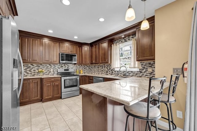 kitchen featuring light tile patterned flooring, appliances with stainless steel finishes, a sink, a peninsula, and backsplash