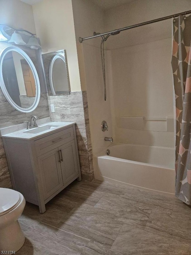 full bathroom featuring vanity, shower / tub combo, tile walls, and toilet