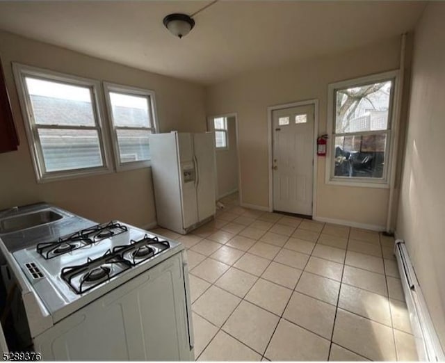 kitchen featuring white appliances, white cabinets, sink, baseboard heating, and plenty of natural light