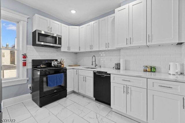 kitchen featuring sink, light stone counters, black appliances, white cabinets, and decorative backsplash