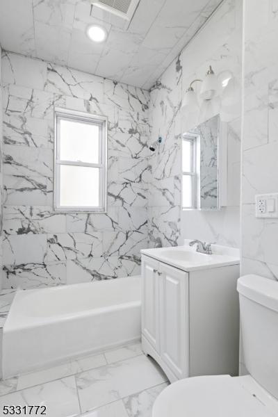 full bathroom with toilet, vanity, and tiled shower / bath