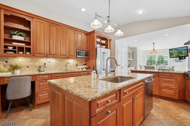 kitchen featuring stainless steel appliances, open shelves, an island with sink, and a sink
