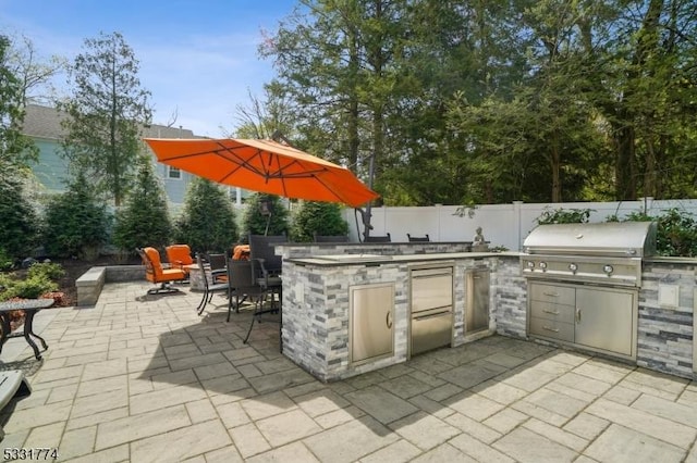 view of patio with exterior kitchen, grilling area, and fence