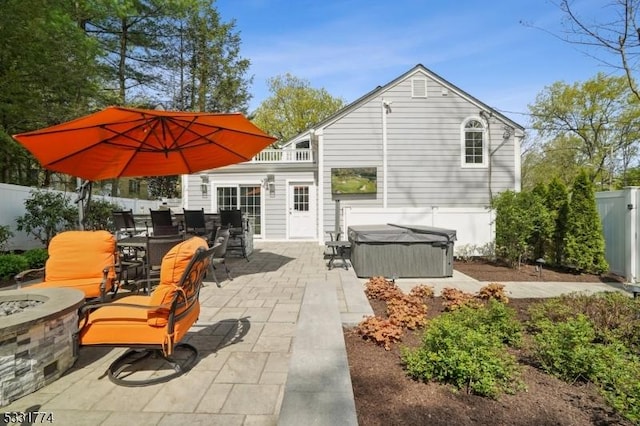 view of patio / terrace featuring a hot tub, a fire pit, a fenced backyard, and outdoor dining space