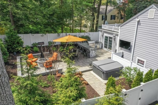exterior space featuring an outdoor bar, an outdoor kitchen, a fenced backyard, and an outdoor fire pit