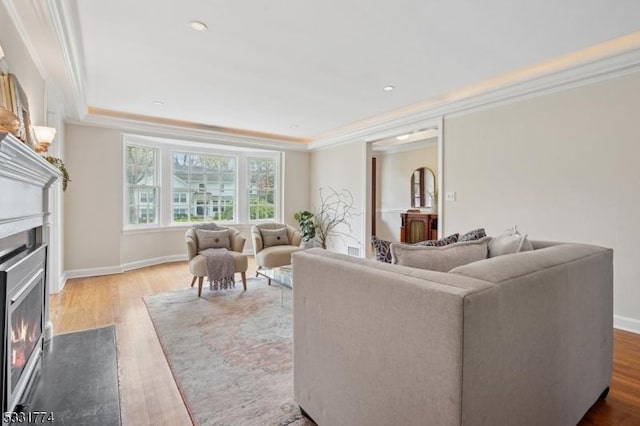 living room featuring ornamental molding, a fireplace with flush hearth, and wood finished floors