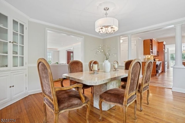 dining space with decorative columns, baseboards, a chandelier, light wood-style floors, and ornamental molding
