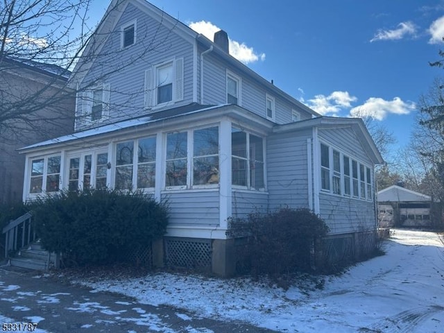 view of snowy exterior with a sunroom