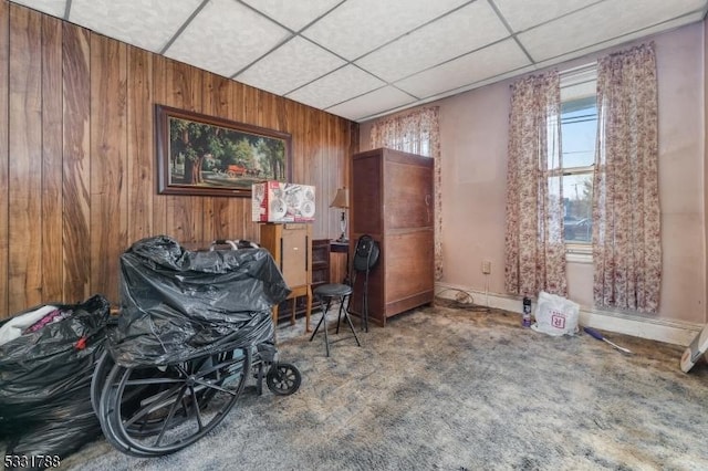 misc room featuring carpet flooring, a paneled ceiling, and wood walls