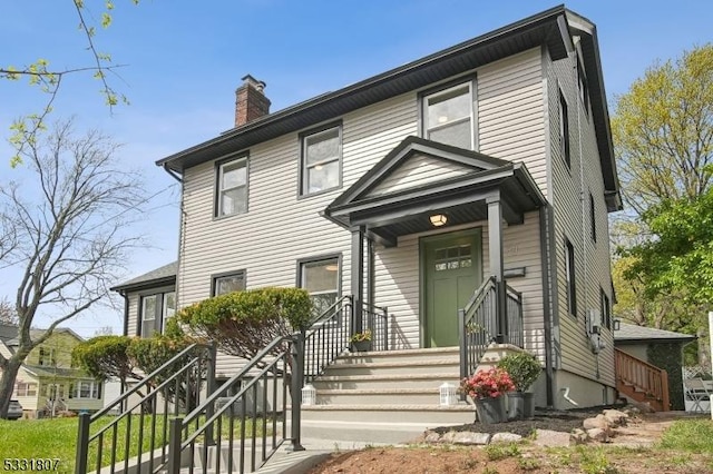 view of front facade featuring stairs and a chimney