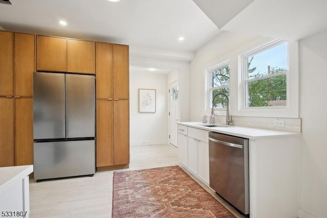 kitchen with a sink, stainless steel appliances, recessed lighting, light wood-style flooring, and light countertops