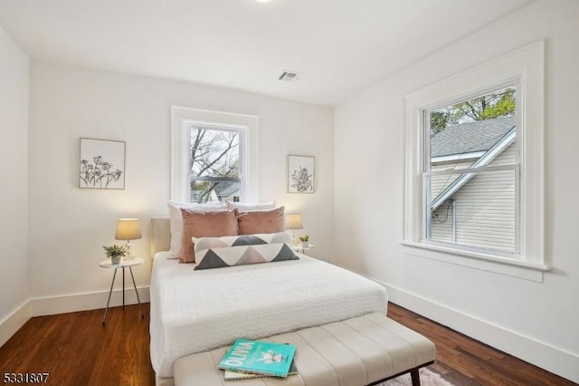 bedroom featuring multiple windows, wood finished floors, visible vents, and baseboards