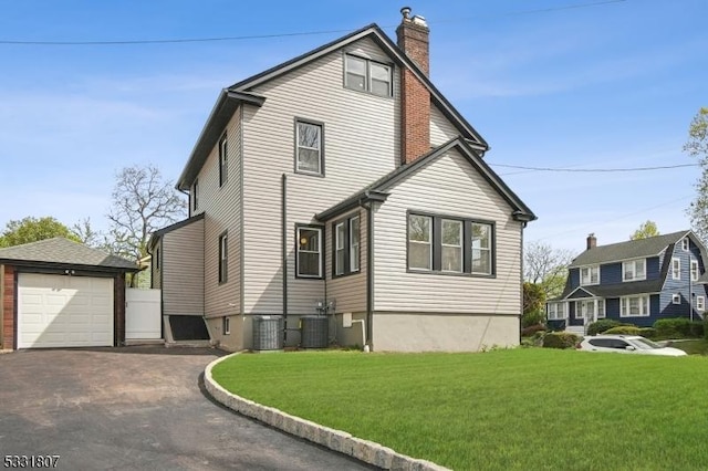 view of property exterior with a chimney, a lawn, a garage, central air condition unit, and aphalt driveway