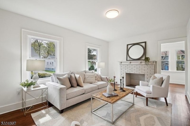 living room featuring a brick fireplace, a wealth of natural light, baseboards, and wood finished floors