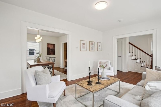 living room featuring baseboards, dark wood-style flooring, and stairway