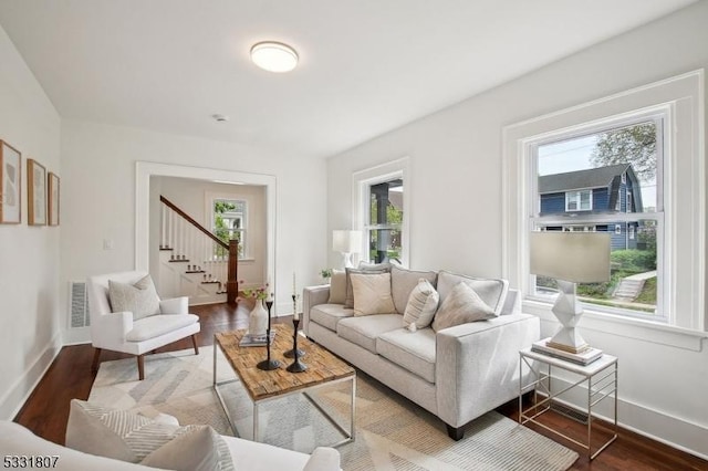 living room with baseboards, stairway, visible vents, and wood finished floors