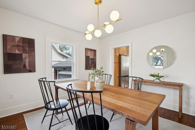 dining space featuring an inviting chandelier, baseboards, and wood finished floors