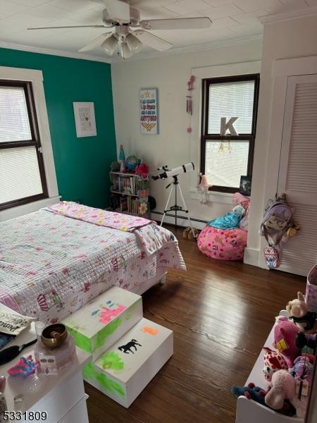 bedroom with ornamental molding, a baseboard radiator, ceiling fan, and dark wood-type flooring