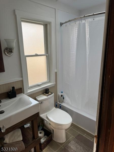 bathroom featuring toilet and shower / bathtub combination with curtain