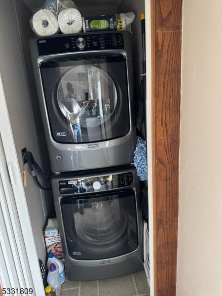 laundry area with tile patterned flooring and stacked washer / drying machine