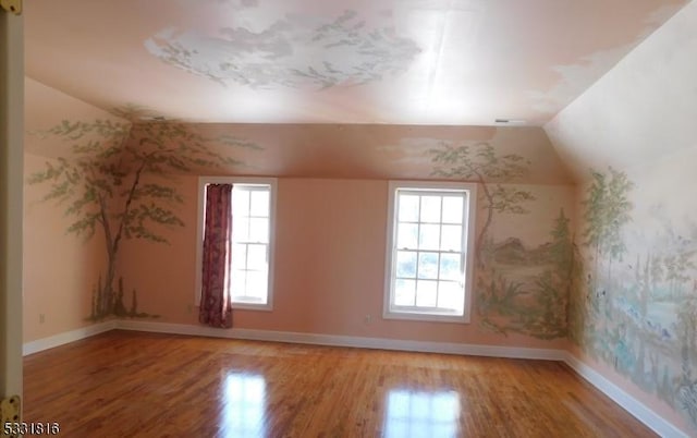 additional living space with hardwood / wood-style floors and vaulted ceiling