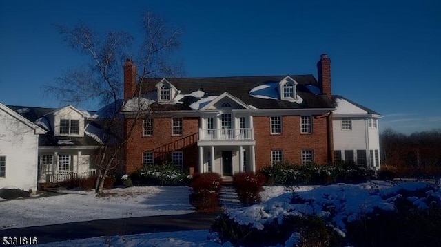 snow covered rear of property featuring a balcony