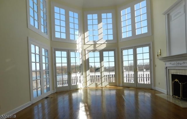 unfurnished living room with a wealth of natural light, french doors, and a high ceiling